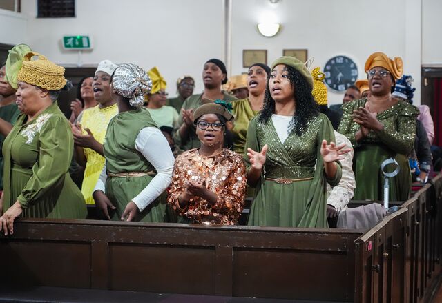 Women standing together in the pews with hands raised.