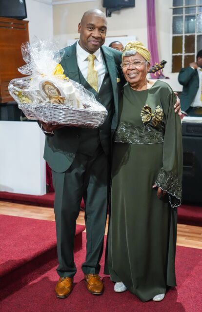 Man and woman smiling together while holding flowers and wrapped gifts.