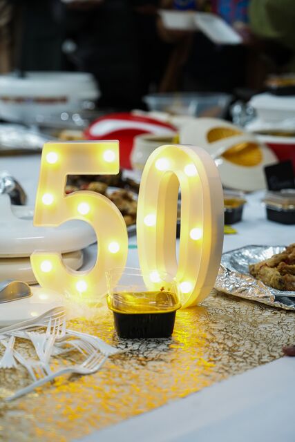 Illuminated gold number 50 decoration on a dining table.